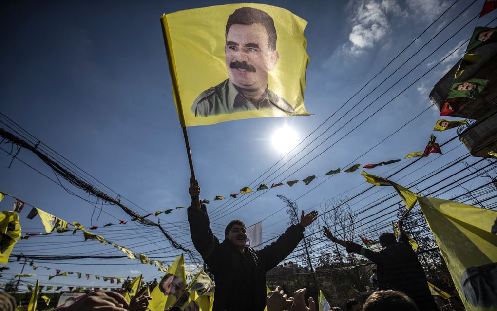 Een demonstrant houdt een vlag vast met daarop Abdullah Ocalan, leider van de PKK, tijdens een demonstratie op 15 februari 2025 in Qamishli, Syrië. Ocalan zit sinds 1999 in de Turkse gevangenis. beeld AFP, Delil Souleiman