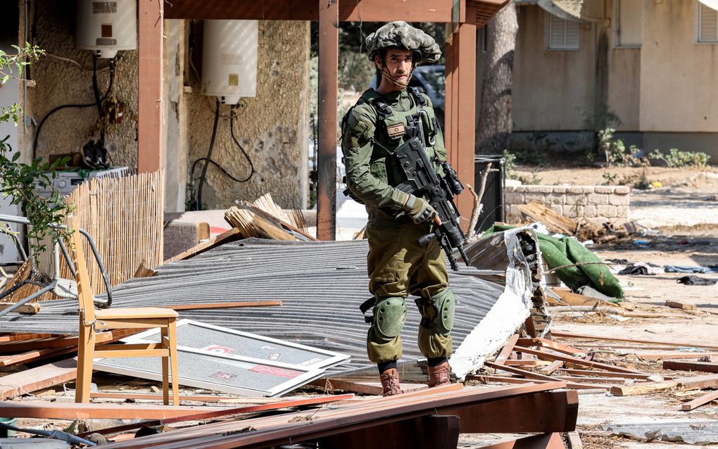 Een Israëlische militair neemt de verwoestingen in kibboets Kfar Aza in ogenschouw, kort na de aanslagen van 7 oktober 2023. beeld AFP, Jack Guez