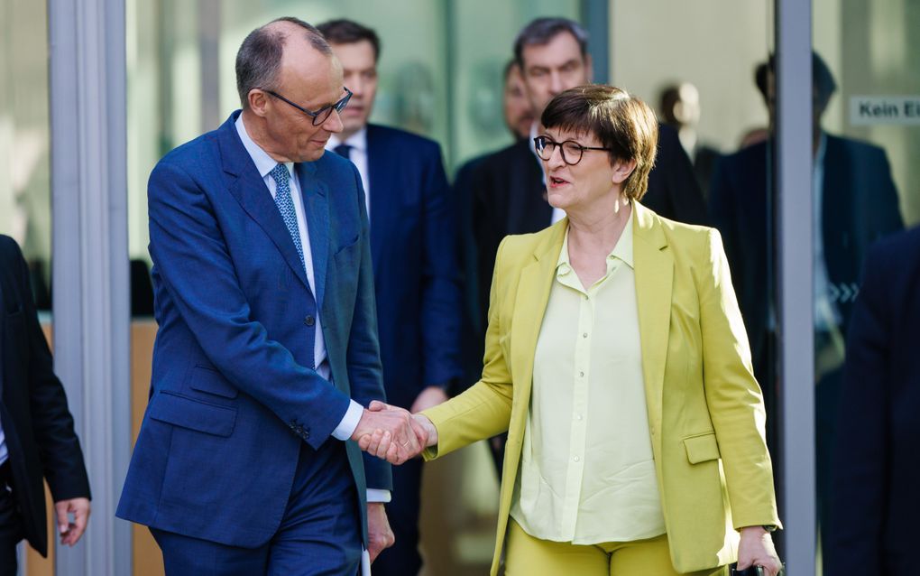 CDU/CSU-leider Friedrich Merz geeft SPD-covoorzitter Saskia Esken zaterdag een hand nadat ze een persconferentie hebben gegeven over de verkennende gesprekken tussen de twee partijen om een regeringscoalitie te vormen. beeld EPA, Clemens Bilan