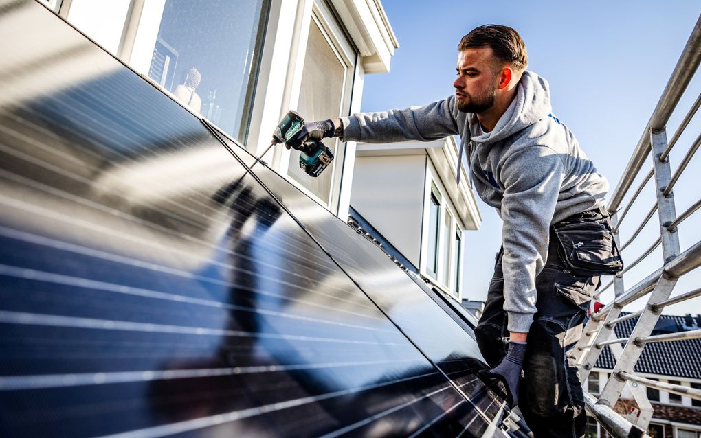 Een installateur plaatst zonnepanelen op het dak van een woning. beeld ANP, Jeffrey Groeneweg