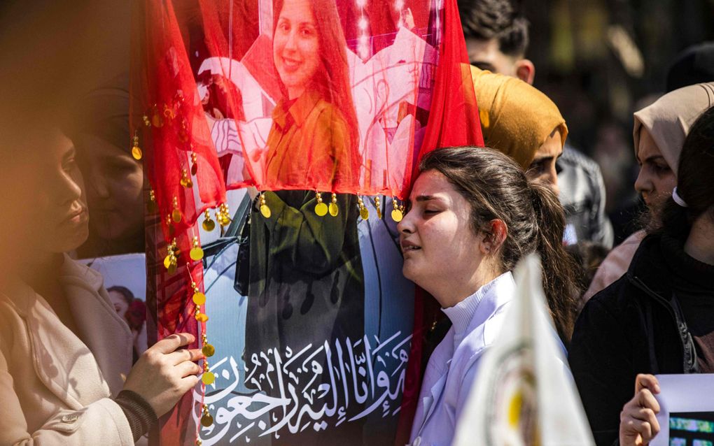 Een jonge vrouw in Qamishli rouwt bij een foto van een slachtoffer van de geweldsuitbarsting in Syrië. Ook christenen werden het slachtoffer van de bloedige wraakacties. beeld AFP, Delil Souleiman