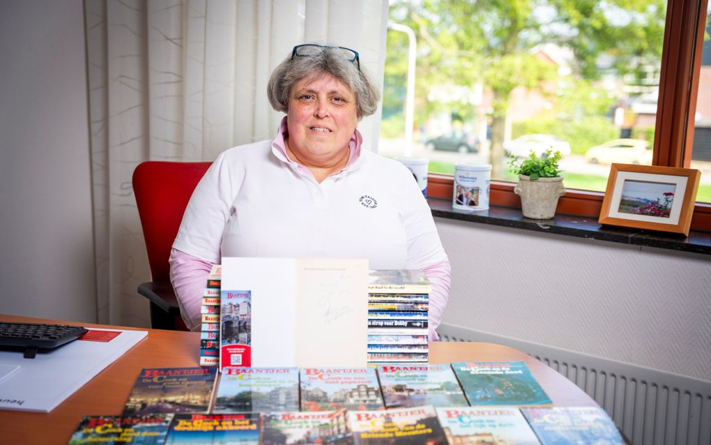 Wilma Kooiman met haar verzameling Baantjers. Het boek met de handtekening staat opengeslagen. beeld Van der Wal Fotografie, Rens de Groot
