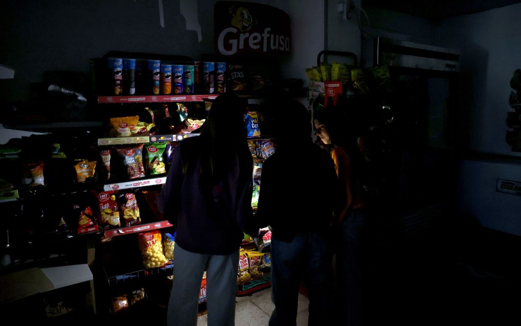 In Spaanse supermarkten werd volop gehamsterd na de grootschalige stroomuitval. Klanten gebruiken de zaklamp van hun telefoon om zich een weg door de winkel te banen. beeld EPA, Alberto Estevez