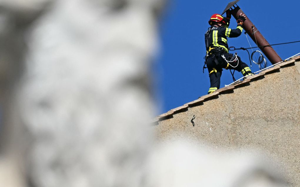Een werkman plaatst de schoorsteenpijp op het dak van de Sixtijnse Kapel in Vaticaanstad, waar straks de witte rook uit moet komen. Op de voorgrond het standbeeld van de apostel Paulus. beeld AFP, Gabriel Bouys