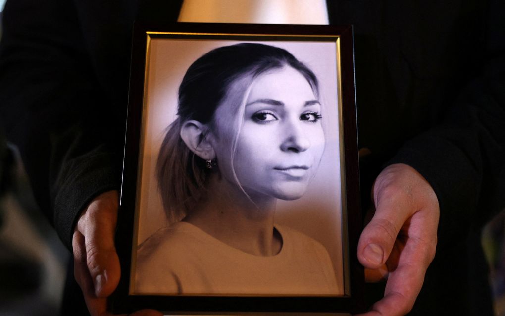 Een collega van de Oekraïense journaliste Viktoria Rosjtsjyna houdt een foto van haar vast tijdens een herdenkingsbijeenkomst in Kyiv. beeld AFP, Anatoli Stepanov