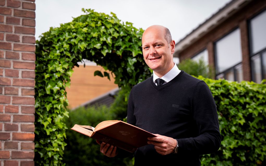 Ds. G.J. Roukens, predikant van Bethábara Alblasserdam, met een boek van zijn favoriete schrijver John Bunyan in zijn handen. beeld Cees van der Wal