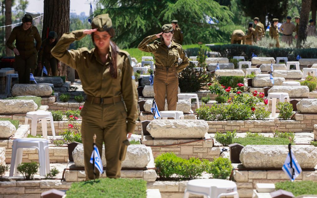 „Wie zich verdiept in het Israëlisch-Palestijns conflict, weet dat dit geen platgeslagen zwart-witverhaal is. Het is een tragisch verhaal van twee volkeren, verweven in een decennialange spiraal van geweld, trauma en wederzijdse pijn.” Foto: Israëlische soldaten salueren bij de graven van omgekomen medesoldaten op de nationale begraafplaats Herzlberg nabij Jeruzalem. beeld AFP, Menahem Kahana