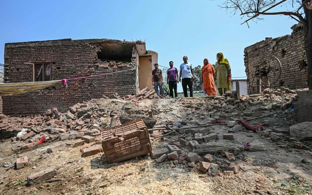 Bewoners van het dorp Pahari Wala kijken naar een door Pakistan vernietigd huis in India. beeld AFP, Money Sharma