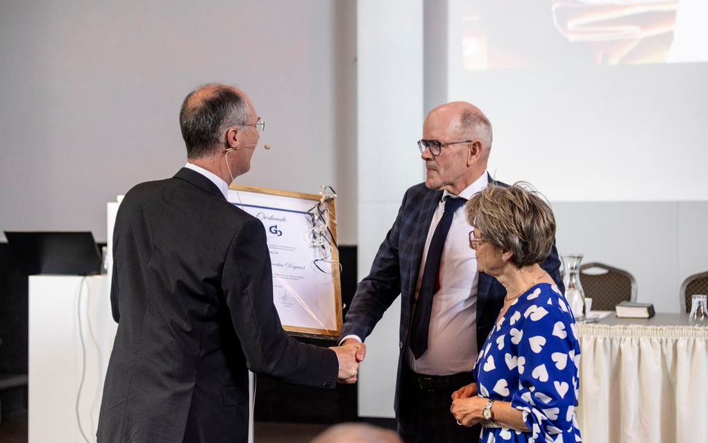 Piet Vergunst (m.) is donderdag in Putten benoemd tot erelid van de Gereformeerde Bond. Hij krijgt uit handen van ds. J.A.W. Verhoeven (l.) een oorkonde. beeld André Dorst