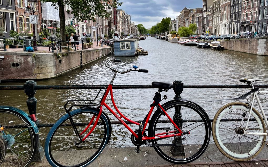 Gracht met aan weerskanten oude herenhuizen, op de voorgrond een rode fiets.