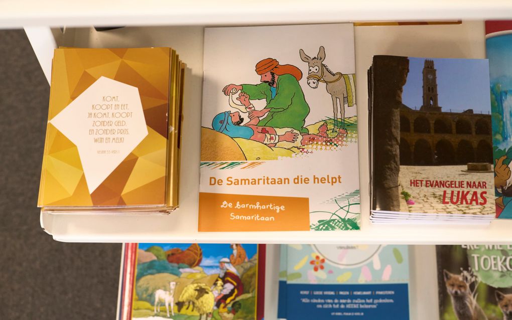 Gekleurde boekjes en paperbacks liggen op een witte stelling