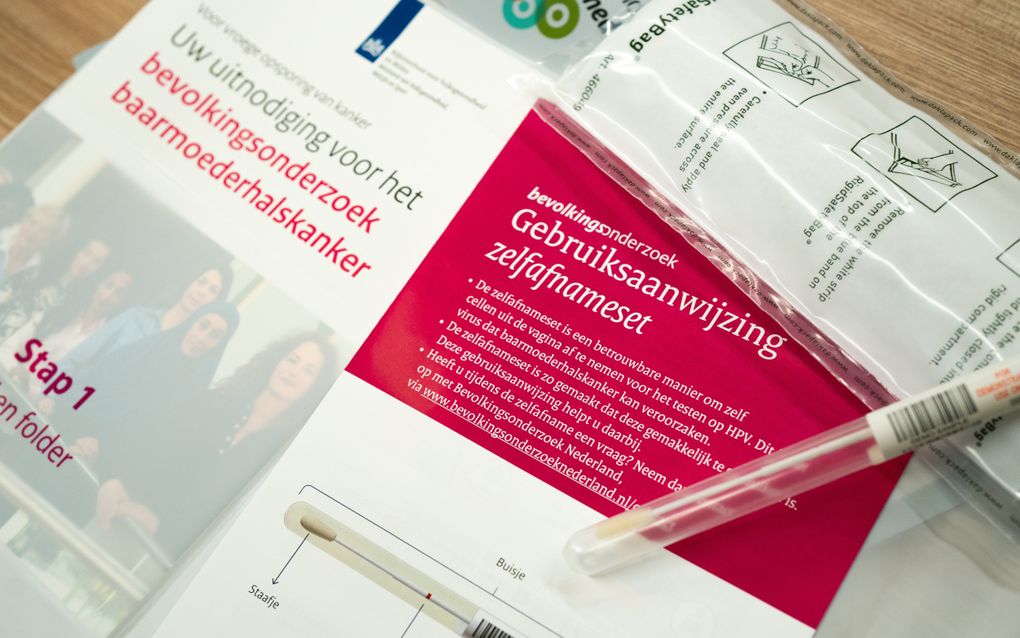 Foto van een folder met een uitnodiging voor het bevolkingsonderzoek baarmoederhalskanker. Op het papier ligt een testbuisje en een gebruiksaanwijzing voor de zelfafnameset.