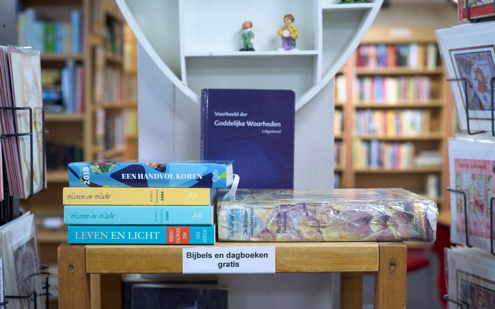 Een tafeltje met boeken. Op de zijkant is een wit papiertje geplakt, met daarop ”Bijbels en dagboeken gratis”