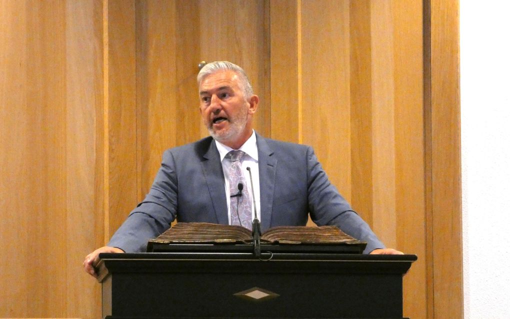 Man in grijs pak op de kansel.