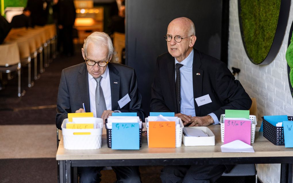 Twee mannen zitten achter een tafel.