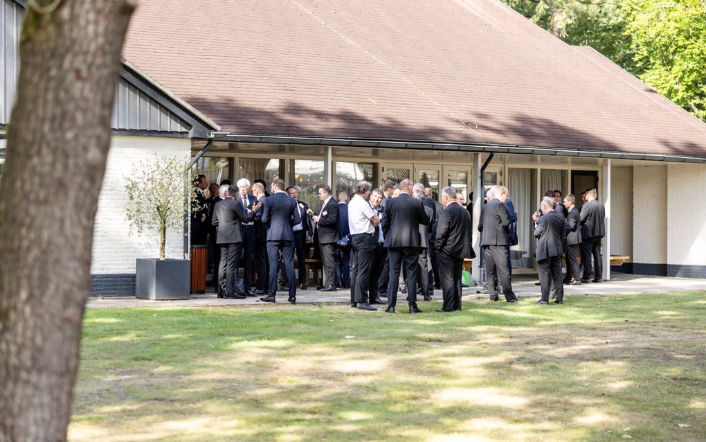 Een groep mannen in pak voor een gebouw.