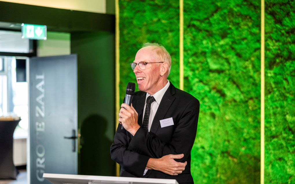 Een man in pak met een microfoon in zijn hand.