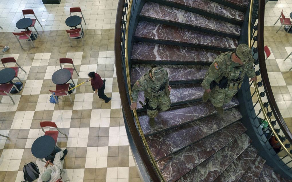 Twee mannen in uniform en met een wapen lopen over een marmeren trap in een winkelcentrum