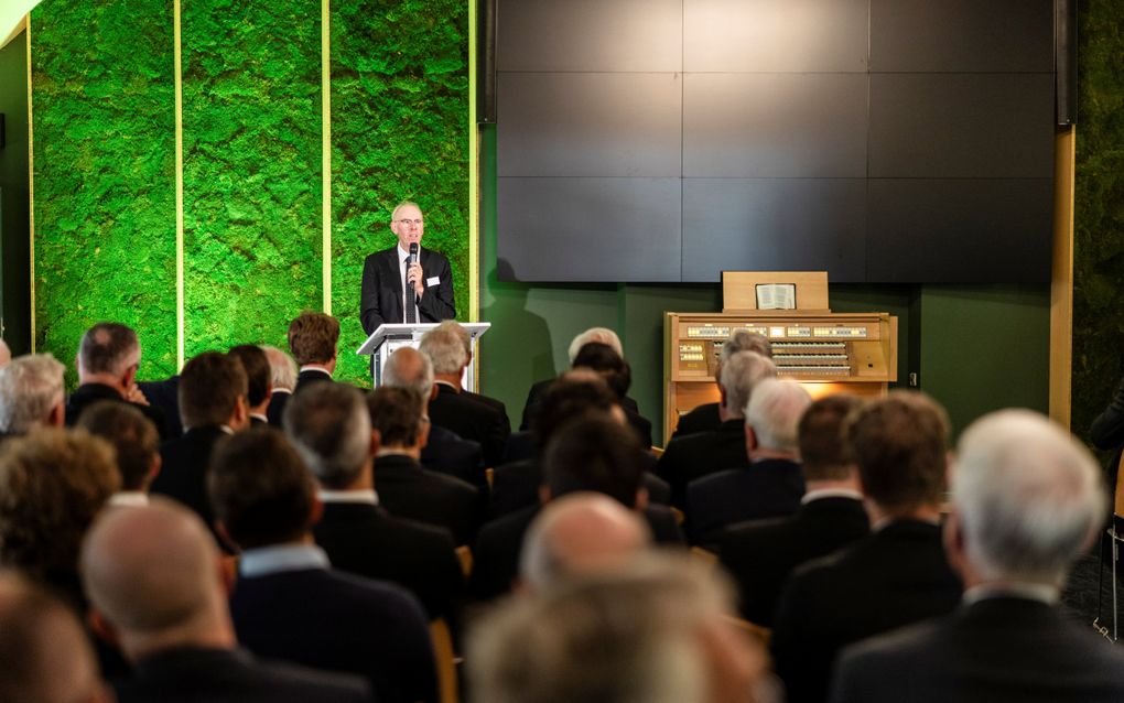 Een man in pak spreekt een menigte toe.