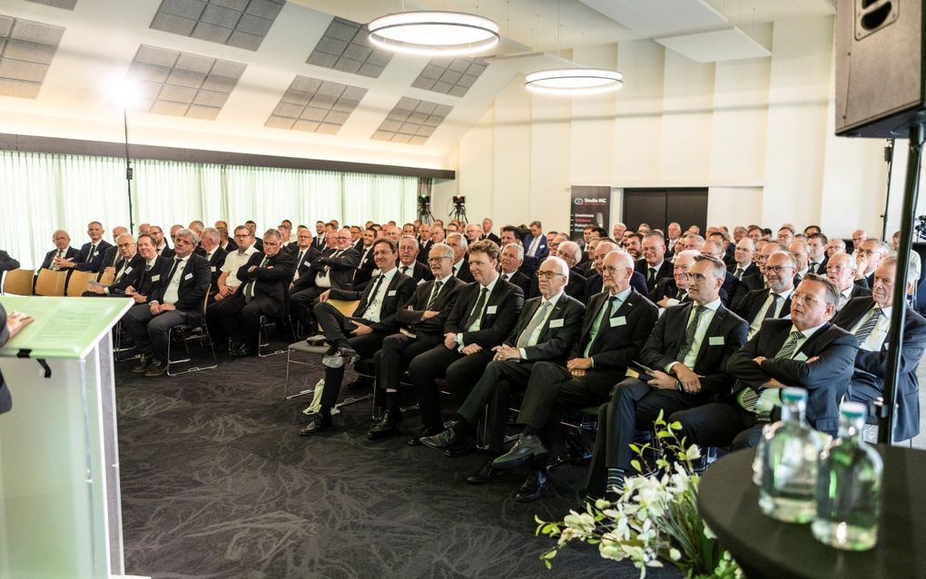Een groep mannen in pak zit op stoelen.