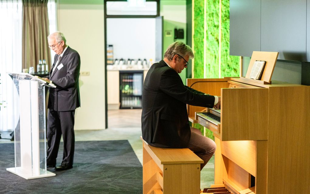 Een man in pak speelt orgel.