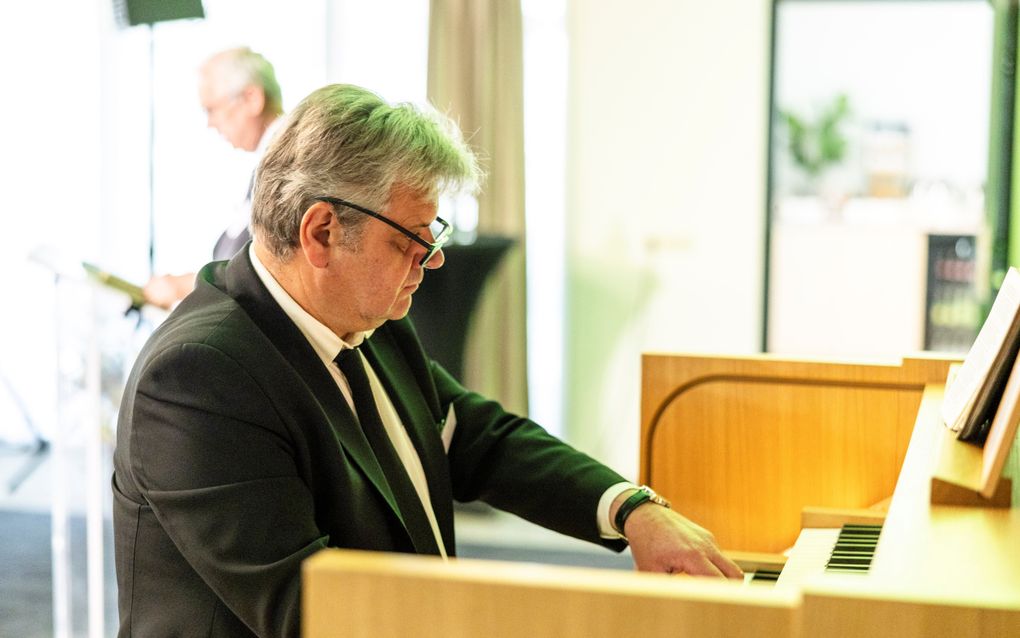 Een man in pak speelt orgel.