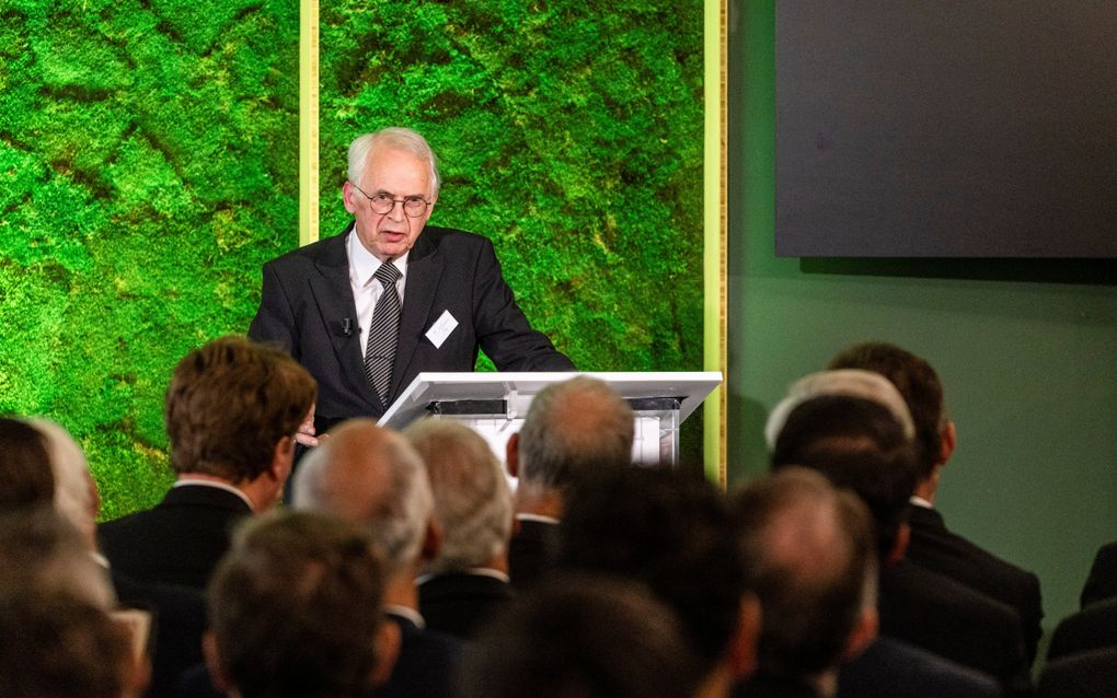 Een man in pak spreekt een menigte toe.