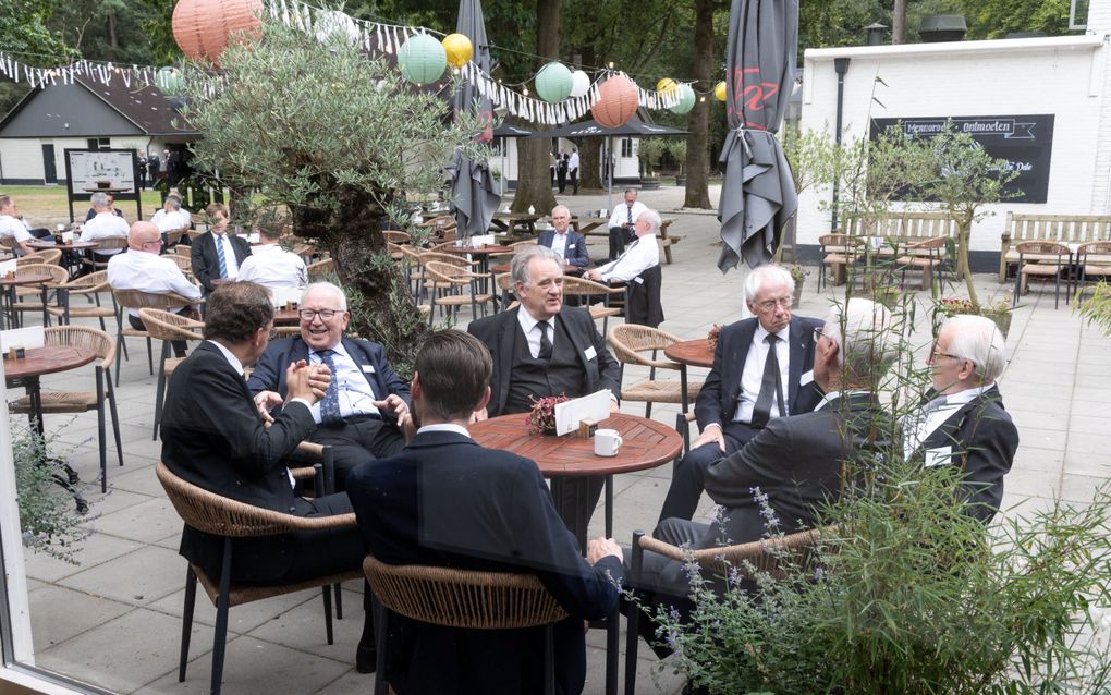 Een groep mannen in pak zit op een terras.