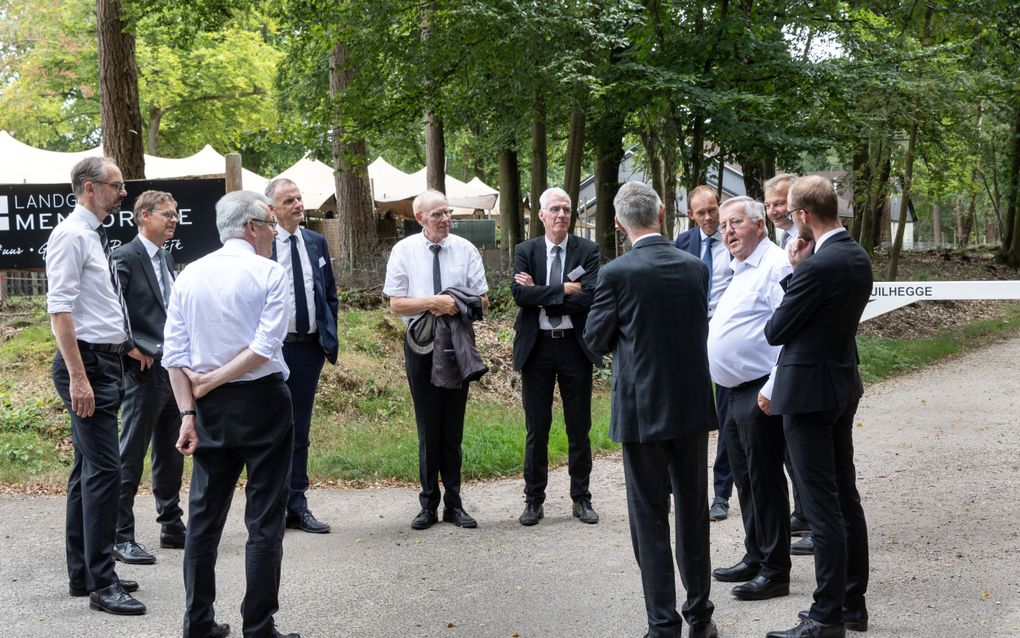 Een groep mannen in pak staat in een kring.