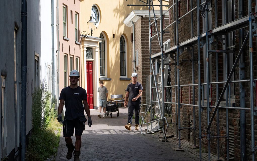 Werklui met helm in een straatje.