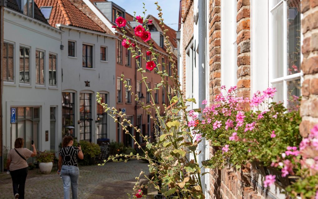 Vrouwen maken foto’s in een straatje met bloemen.