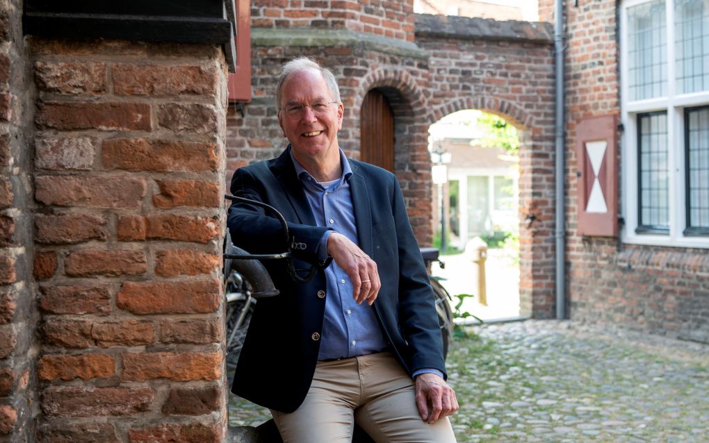 Lachende man naast poortje.