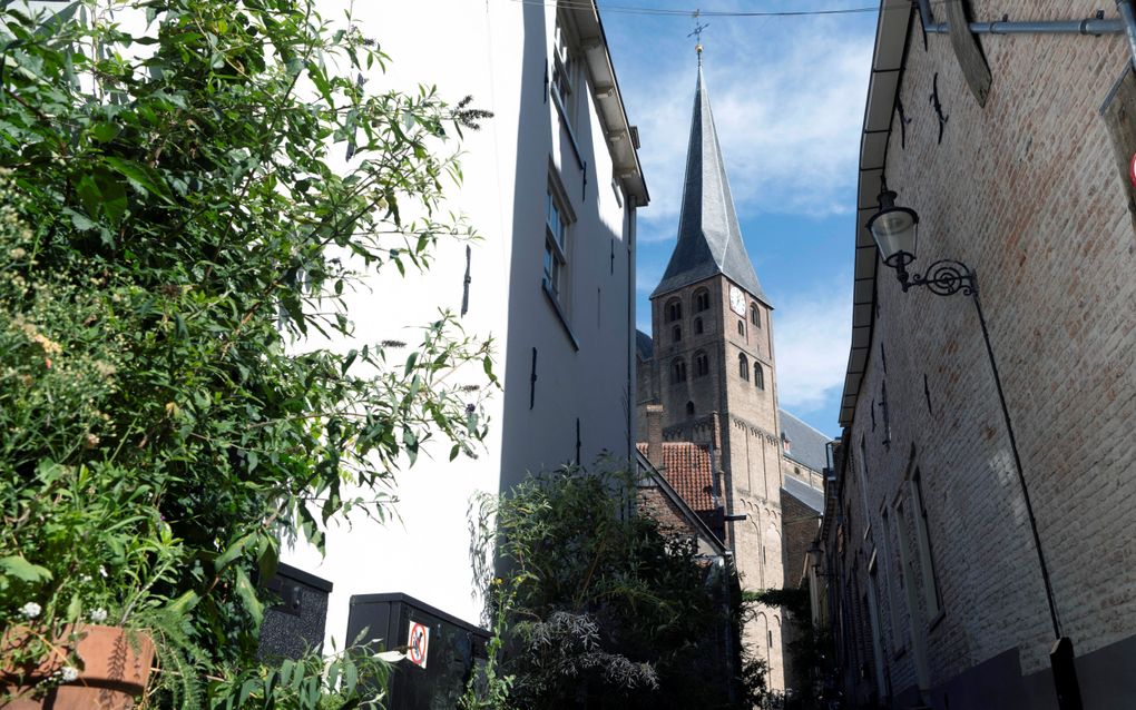 Kerktoren zichtbaar tussen twee oude huizen.