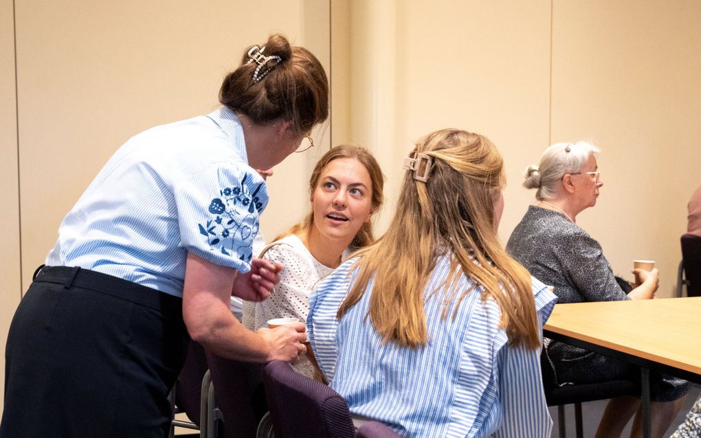 Enkele vrouwen drinken koffie aan een tafel en zijn in gesprek.