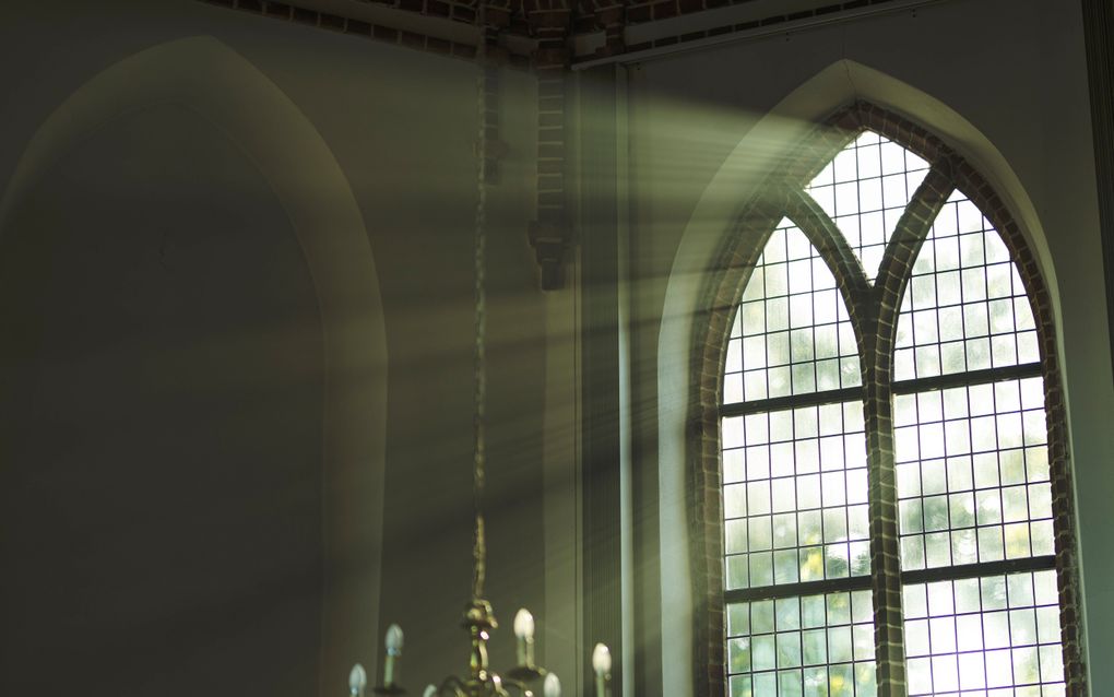 Zonnestralen breken door een glas-in-loodraam in een oude kerk.