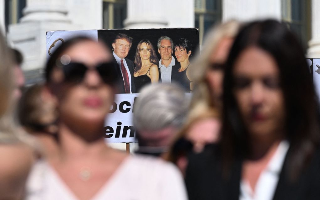 Vrouwen staan naast elkaar. Ze houden een banner omhoog met de afbeelding van vier mensen. 