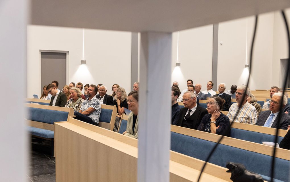 Mensen in kerkbanken luisteren naar een spreker.