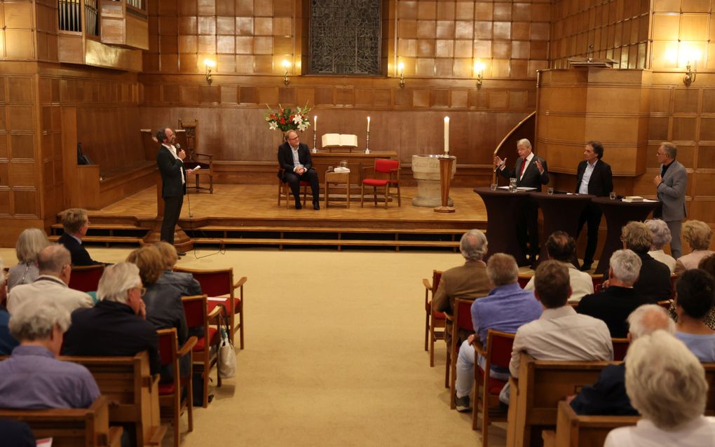 Tijdens de forumbespreking. Achter de tafel rechts is Donner aan het woord, hij spreekt met gebaren.
