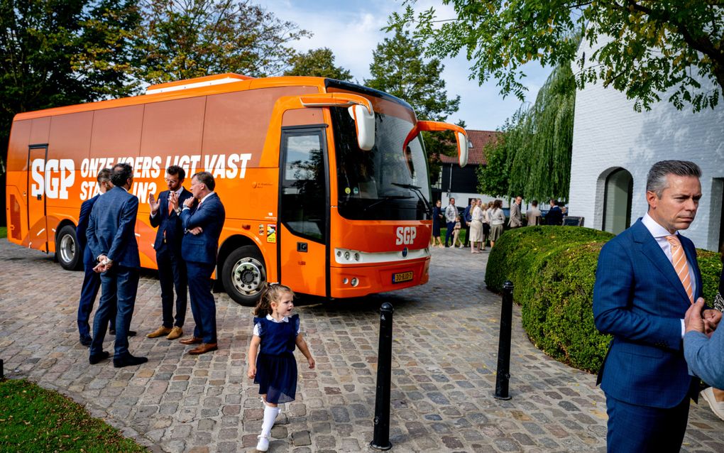 Mannen in pak en een oranje bus.