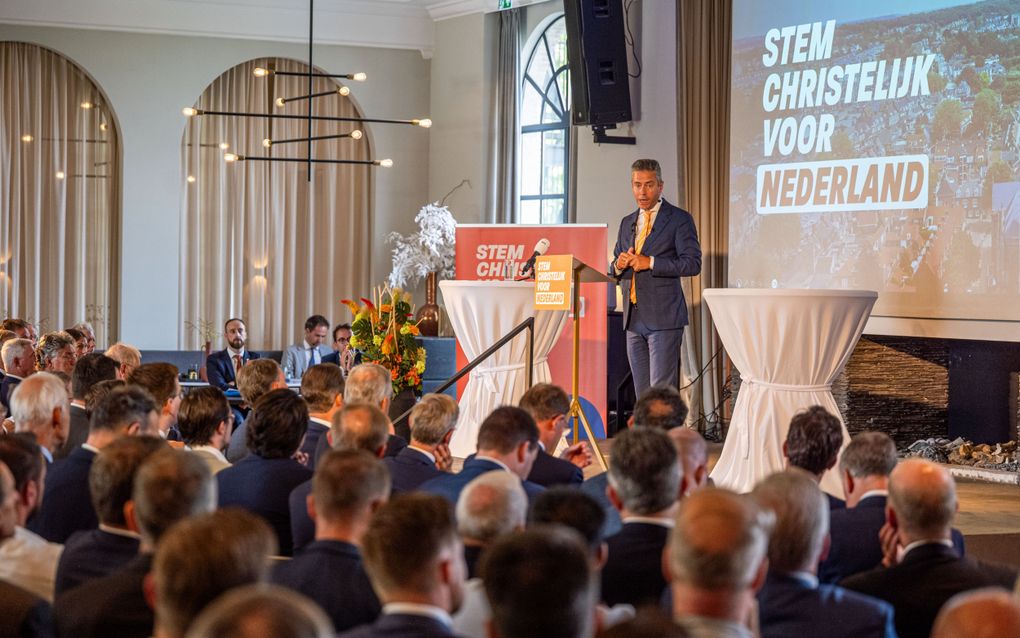 Man staat op podium voor een zaal met mensen.