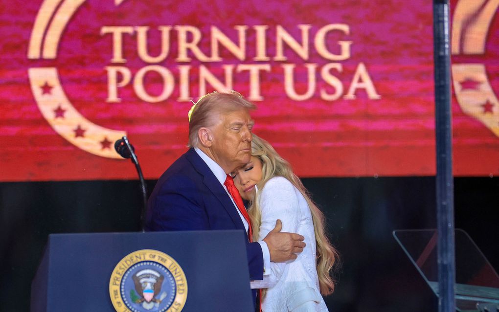 Man met blond haar en blauw pak omhelst een in het wit geklede vrouw met lang, blond haar.