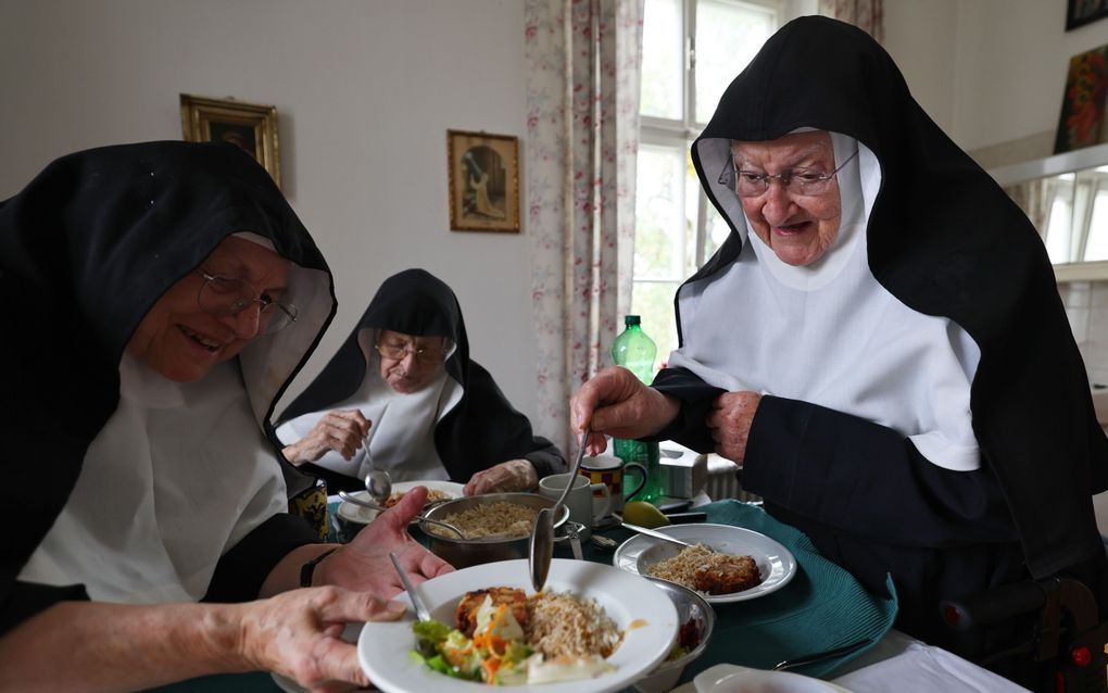 Drie oude vrouwen bij hun bord met eten.