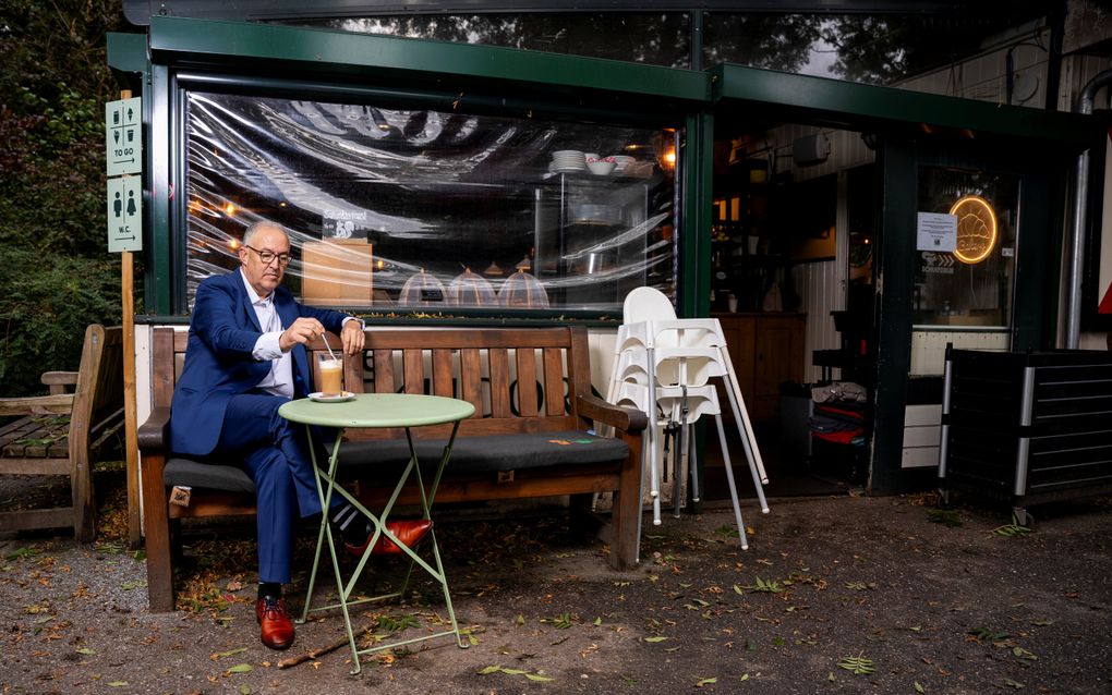 Man roert in een glas drinken op het terras van een snackbar in het Kralingse Bos.