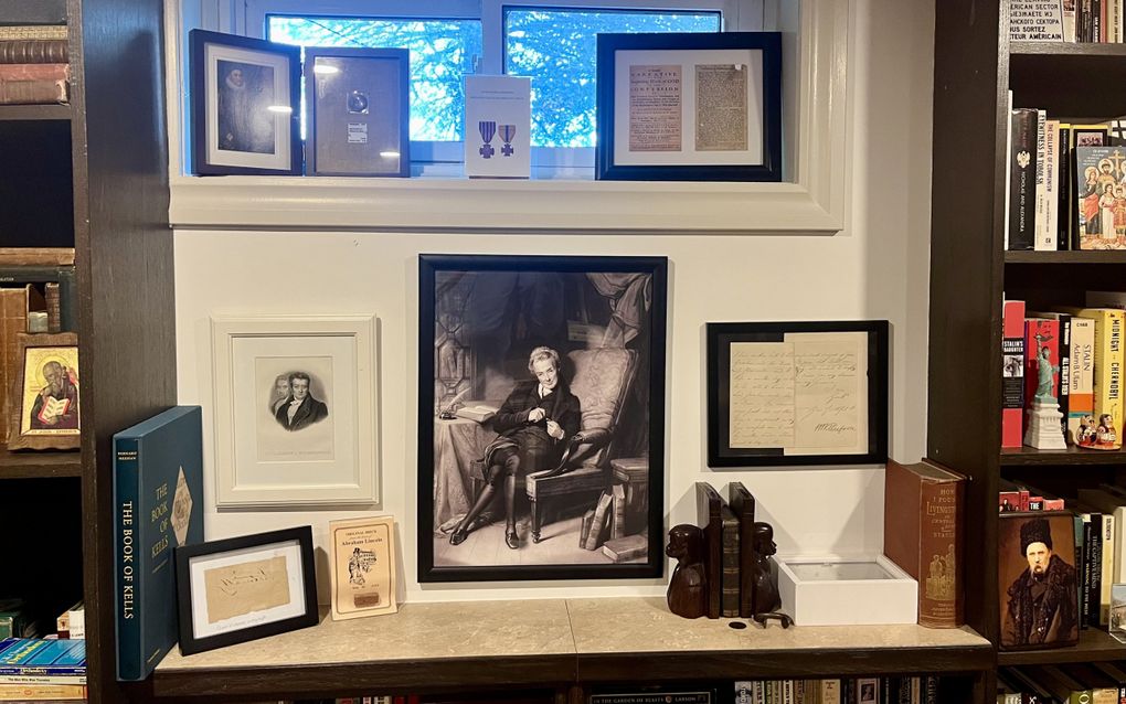 Allemaal lijsten met portretten en historische boekpagina’s hangen aan een muur.