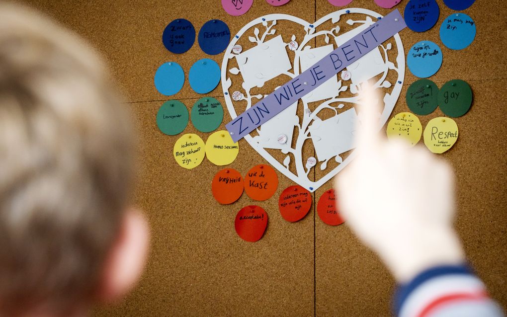Een jongetje steekt zijn vinger op. Achter hem hangt een groot hart met de tekst ”Zijn wie je bent”, en daaromheen woorden die hierbij zouden passen, zoals ”respect”.