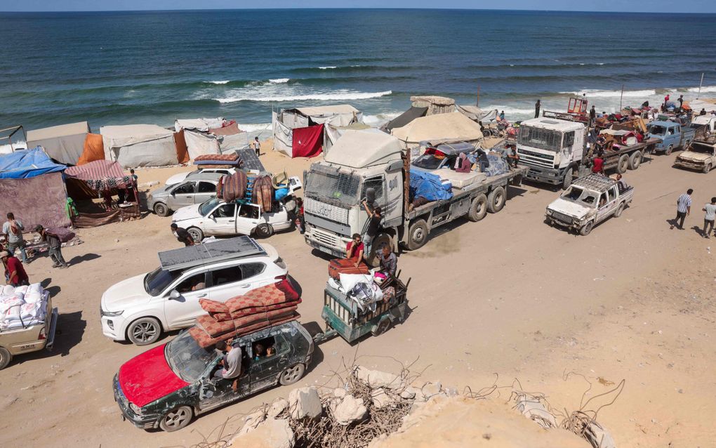 Auto’s en vrachtwagens rijden over zandweg langs de kust.