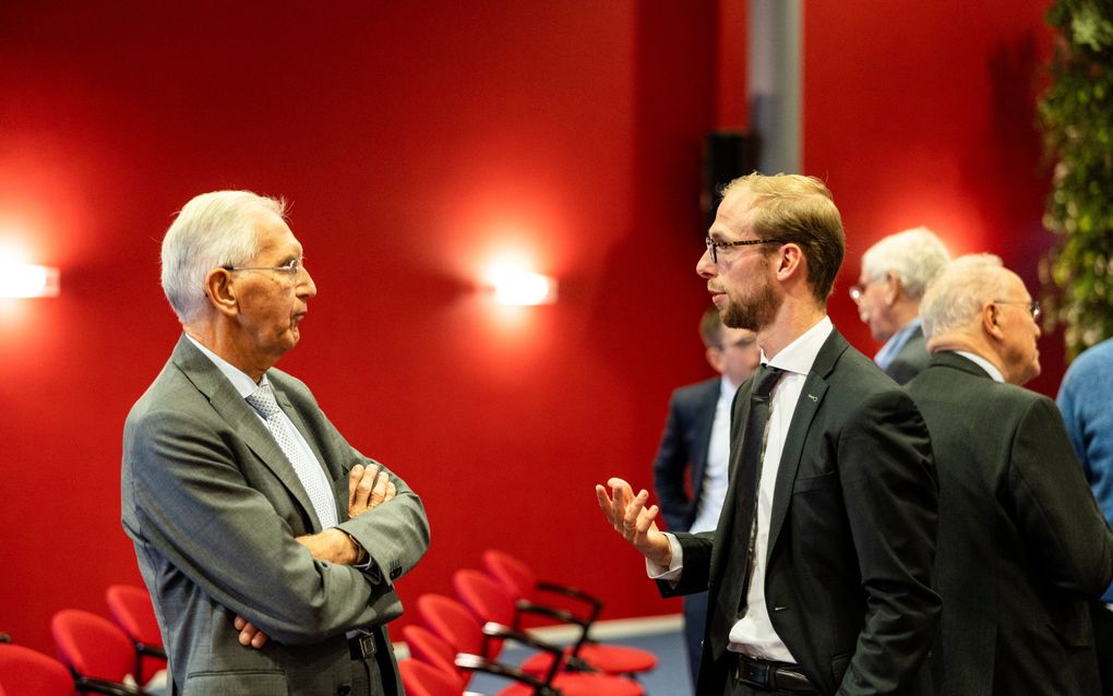 Twee mannen, in pak, met elkaar in gesprek.