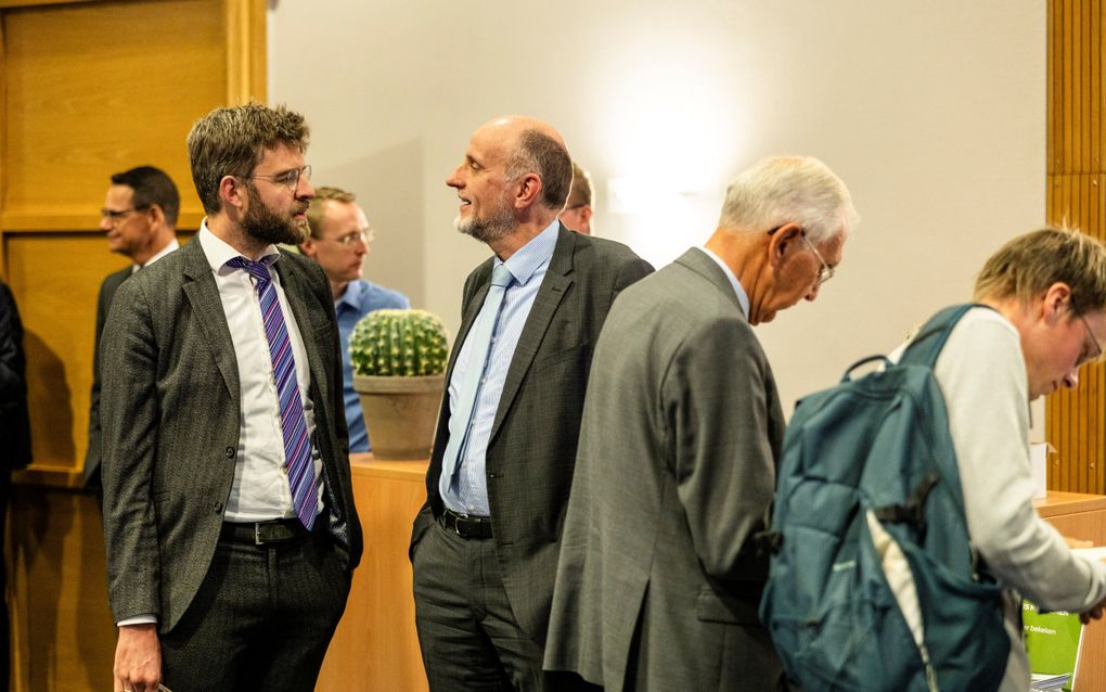 Mannen, in pak, met elkaar in gesprek.
