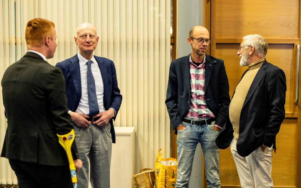 Vier mannen, staand, met elkaar in gesprek.