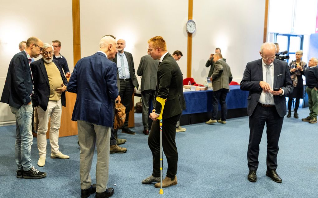 Mannen, in pak, met elkaar in gesprek.